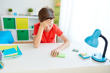 Image showing tired student boy with smartphone at home