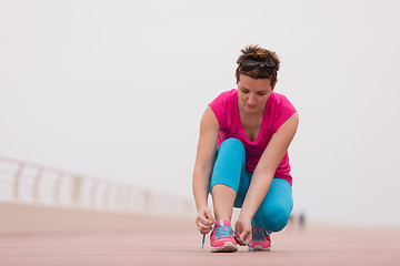 Image showing Young woman tying shoelaces on sneakers