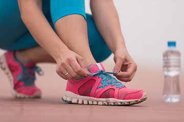 Image showing Young woman tying shoelaces on sneakers