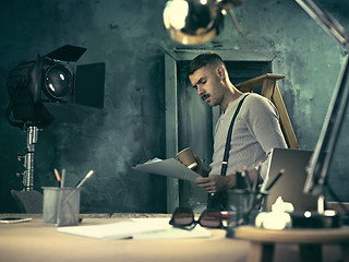 Image showing Portrait of a bearded businessman who is checking details of his upcoming meeting in his notebook and typing.