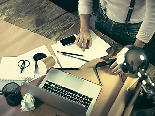 Image showing Vintage hipster wooden desktop top view, male hands using a laptop and holding a pencil