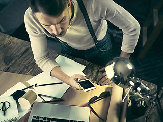 Image showing Portrait of a bearded businessman who is working with his notebook at loft studio.