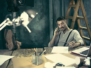 Image showing Portrait of a bearded businessman who is working with his notebook at loft studio.