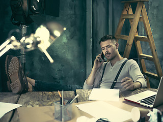 Image showing Portrait of a bearded businessman who is working with his notebook at loft studio.