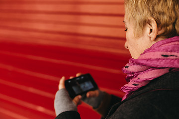 Image showing Woman texting at red wall