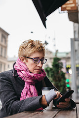 Image showing Woman browsing smartphone in outside cafe