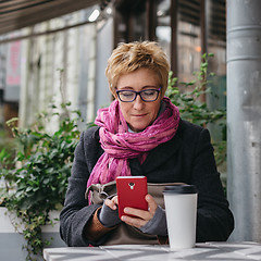 Image showing Smiling woman with phone in cafe