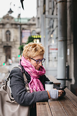 Image showing Woman browsing smartphone in outside cafe