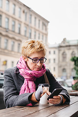 Image showing Woman browsing smartphone in outside cafe