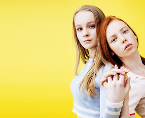 Image showing lifestyle people concept: two pretty young school teenage girls having fun happy smiling on yellow background closeup