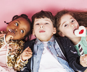 Image showing lifestyle people concept: diverse nation children playing together, caucasian boy with african little girl holding candy happy smiling 