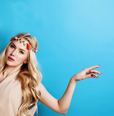 Image showing young pretty blond girl with curly blond hair and little flowers happy smiling on blue sky background, lifestyle people concept closeup