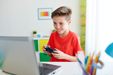 Image showing boy with gamepad playing video game on laptop