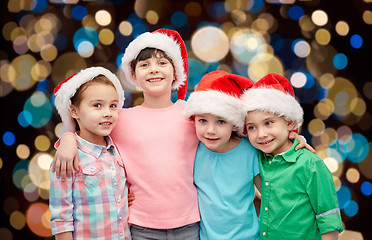 Image showing happy little children in santa hats hugging