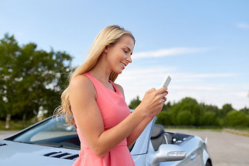 Image showing young woman with smartphone at convertible car