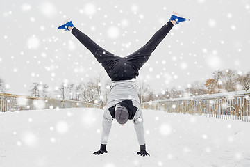 Image showing young man doing handstand in winter