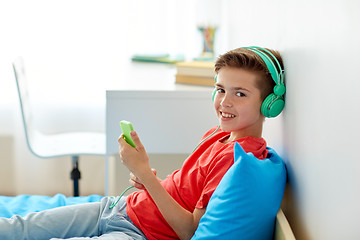 Image showing happy boy with smartphone and headphones at home