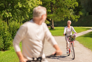 Image showing happy senior couple riding bicycles at summer park