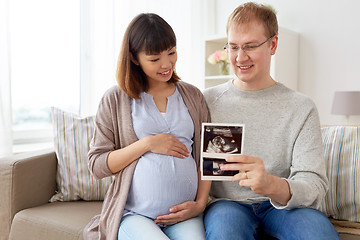 Image showing happy couple with ultrasound images at home