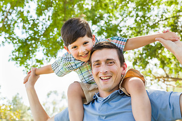 Image showing Mixed Race Father and Son Playing Piggyback Together in the Park