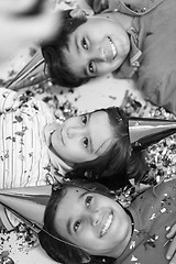 Image showing kids  blowing confetti while lying on the floor