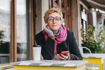 Image showing Dreamy woman with phone in cafe