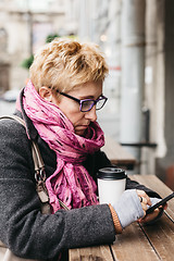 Image showing Woman browsing smartphone in outside cafe