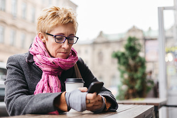 Image showing Woman browsing phone in outside cafe