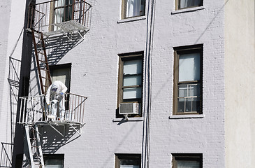 Image showing Painter dressed in coveralls, painting metal fire escape white 