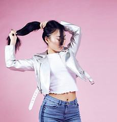 Image showing young pretty smiling asian korean girl wearing modern fashion clothers on pink background, lifestyle people concept closeup