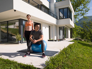 Image showing woman and personal trainer doing exercise with pilates ball