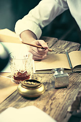 Image showing Writer at work. Handsome young writer sitting at the table and writing something in his sketchpad