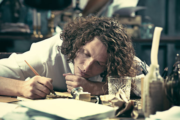 Image showing Writer at work. Handsome young writer sitting at the table and writing something in his sketchpad