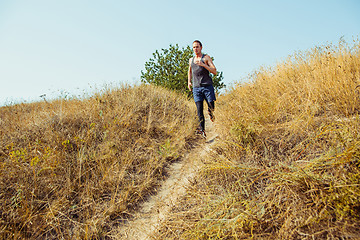 Image showing Running sport. Man runner sprinting outdoor in scenic nature. Fit muscular male athlete training trail running for marathon run.