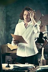 Image showing Writer at work. Handsome young writer standing near the table and making up something in his mind