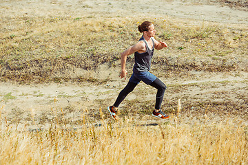 Image showing Running sport. Man runner sprinting outdoor in scenic nature. Fit muscular male athlete training trail running for marathon run.