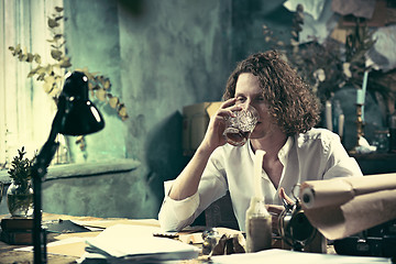 Image showing Writer at work. Handsome young writer sitting at the table and writing something in his sketchpad