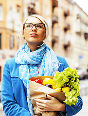 Image showing young pretty blond woman with food in bag walking on street