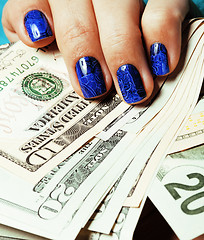 Image showing close up fingers with deep blue creative pattern manicure holding dollars