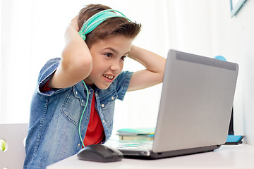 Image showing boy in headphones playing video game on laptop