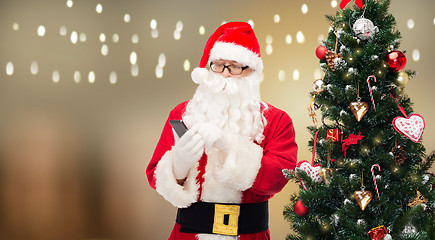 Image showing santa claus with smartphone at christmas tree