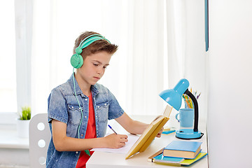 Image showing student boy in headphones writing to notebook