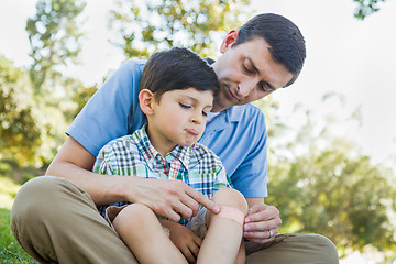 Image showing Loving Father Puts a Bandage on the Elbow of His Young Son in th