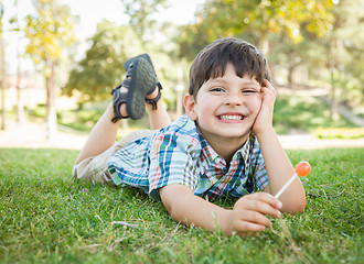 Image showing Handsome Young Boy Enjoying His Lollipop Outdoors on the Grass.