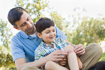 Image showing Loving Father Puts a Bandage on the Elbow of His Young Son in th