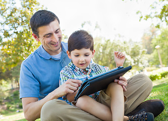 Image showing Happy Father and Son Playing on a Computer Tablet Outside.