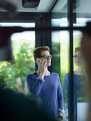 Image showing young women using mobile phone by the window