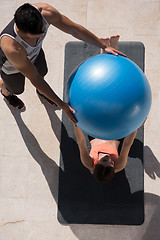 Image showing woman and personal trainer doing exercise with pilates ball