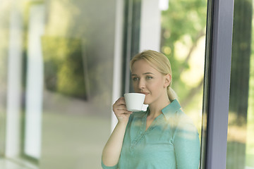 Image showing young woman drinking morning coffee by the window