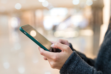Image showing Woman sending sms on mobile phone in shopping mall